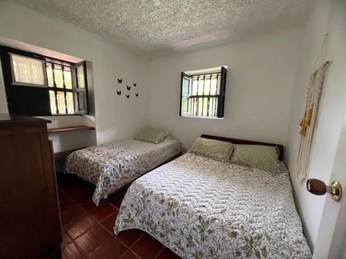 two beds in a room with two windows at casona torremolinos in Moniquirá