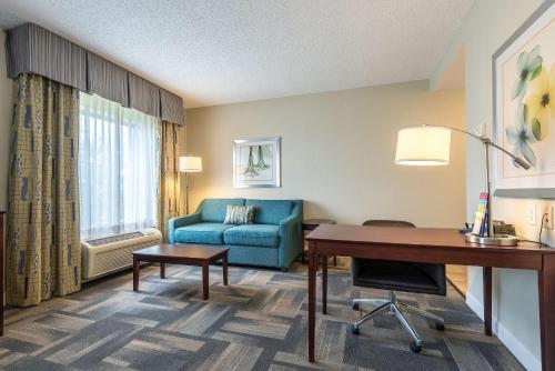 a hotel room with a desk and a blue couch at Hampton Inn & Suites Orlando-South Lake Buena Vista in Kissimmee