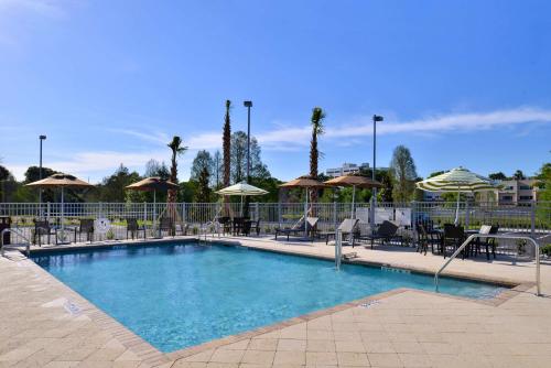 オーランドにあるHampton Inn & Suites Orlando/Downtown South - Medical Centerの大型スイミングプール(椅子、パラソル付)