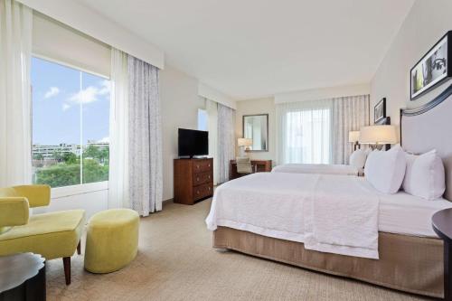 オーランドにあるHampton Inn & Suites Orlando/Downtown South - Medical Centerのベッドと大きな窓が備わるホテルルームです。