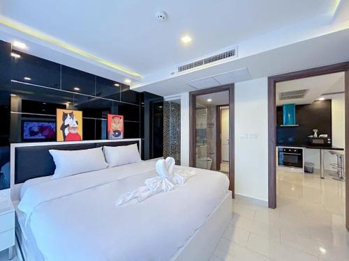 Un dormitorio con una gran cama blanca y una cocina. en Grand Avenue Residence condominium, en Pattaya central