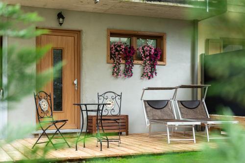 a house with two chairs and a table on a porch at AL RANCH WELLNESS CADORE DOLOMITI APARTMENTS vicino Cortina Olimpiadi 2026 e Misurina Tre Cime Lavaredo in Pieve di Cadore