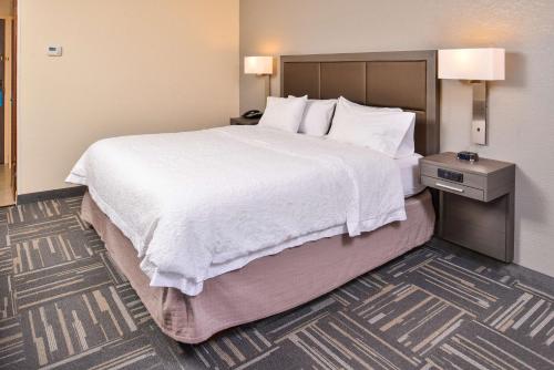 a hotel room with a large bed with white sheets and pillows at Hampton Inn Closest to Universal Orlando in Orlando