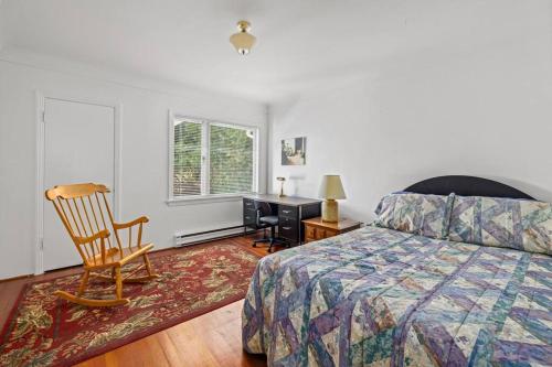 a bedroom with a bed and a chair and a desk at Seaside Country Cottage in Saanichton