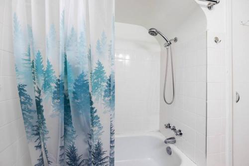 a bathroom with a shower curtain with trees on it at Seaside Country Cottage in Saanichton