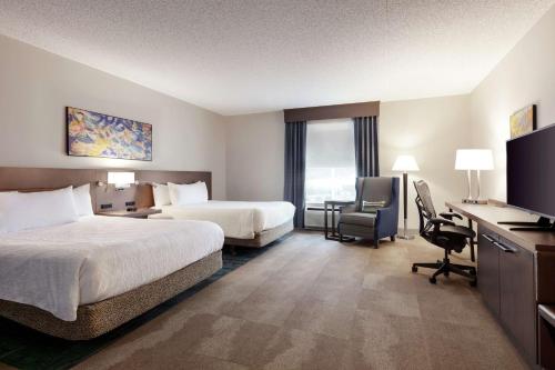 a hotel room with two beds and a desk at Hilton Garden Inn Harrisburg East in Harrisburg