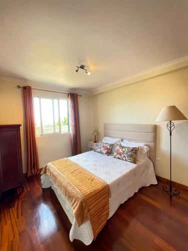 a bedroom with a large bed and a window at Cantinho da Té in Câmara de Lobos