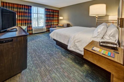 a hotel room with a bed and a flat screen tv at Hampton Inn & Suites Memphis Germantown in Memphis