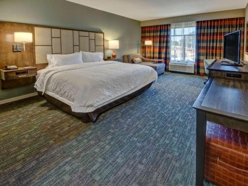 a hotel room with a bed and a flat screen tv at Hampton Inn & Suites Memphis Germantown in Memphis