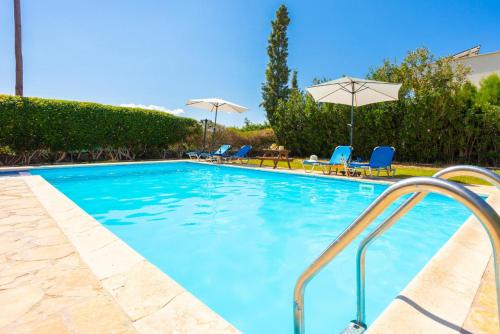 a swimming pool with blue chairs and an umbrella at Villa Tsikkos Tessera in Argaka