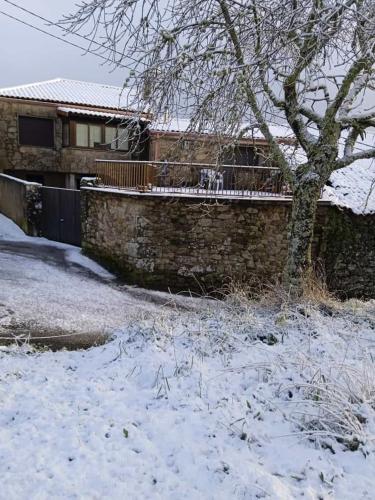 a snow covered yard with a brick wall and a tree at Zoqueiro1 in Pantón