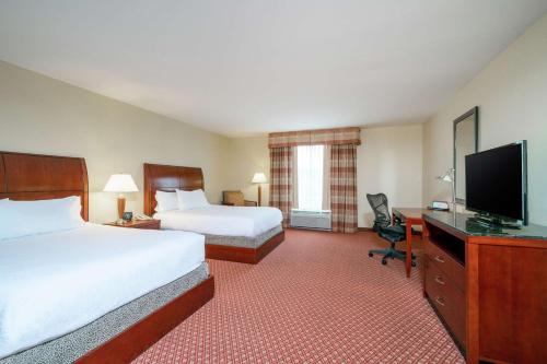 a hotel room with two beds and a flat screen tv at Hilton Garden Inn Morgantown in Morgantown