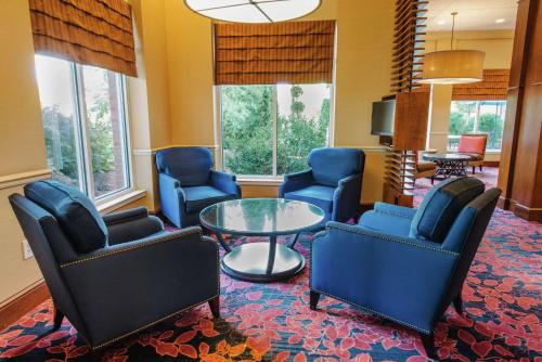 a living room with blue chairs and a glass table at Hilton Garden Inn Manchester Downtown in Manchester