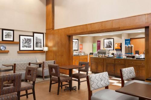 a restaurant with tables and chairs and a counter at Hampton Inn & Suites by Hilton Manchester Bedford in Bedford