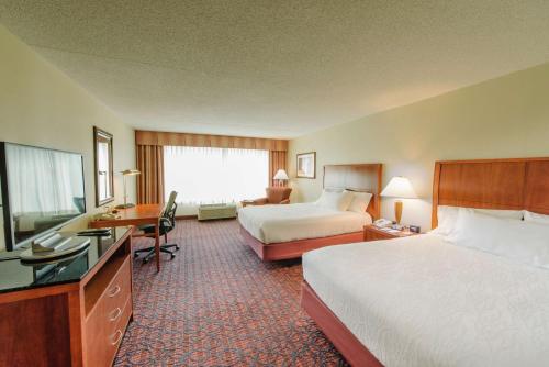 a hotel room with two beds and a desk at Hilton Garden Inn Manchester Downtown in Manchester