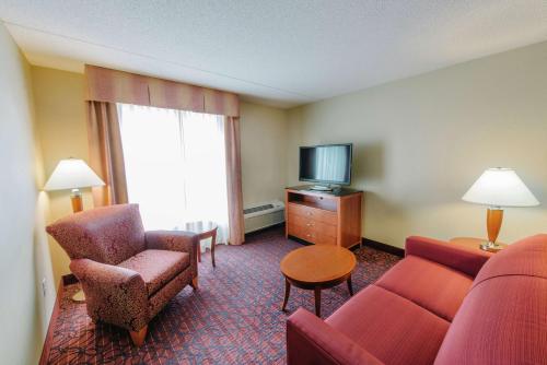 a hotel room with a couch and a chair and a television at Hilton Garden Inn Manchester Downtown in Manchester