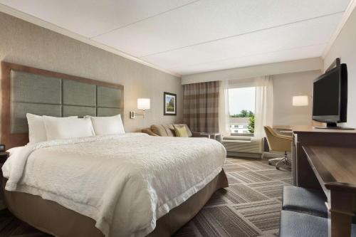 a hotel room with a bed and a flat screen tv at Hampton Inn & Suites by Hilton Manchester Bedford in Bedford