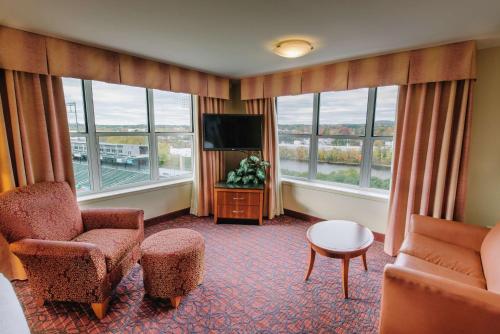 a hotel room with a tv and chairs and windows at Hilton Garden Inn Manchester Downtown in Manchester