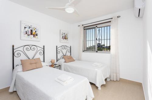 2 Betten in einem weißen Zimmer mit Fenster in der Unterkunft Villa Alegria in Torrox