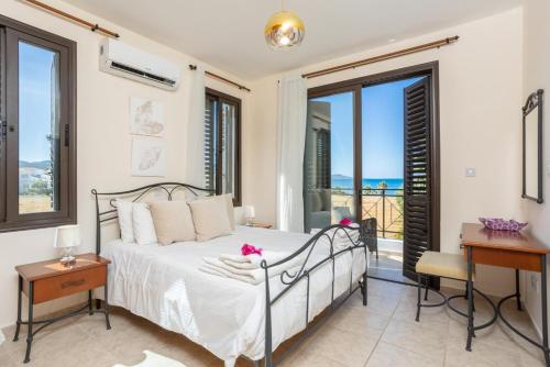 a bedroom with a bed and a balcony with the ocean at Villa Anna in Lachi