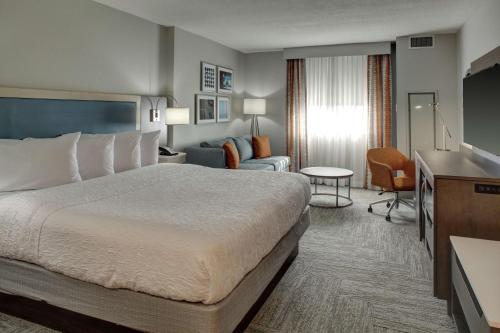 a hotel room with a bed and a living room at Hampton Inn & Suites Miami Airport South/Blue Lagoon in Miami