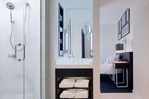 a bathroom with a shower and a sink with a mirror at Gale South Beach, Curio Collection By Hilton in Miami Beach