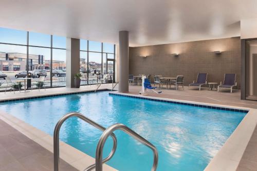 a pool in a hotel with chairs and a table at Hilton Garden Inn Milwaukee Brookfield Conference Center in Brookfield