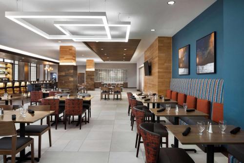 a dining room with wooden tables and chairs at Hilton Garden Inn Milwaukee Brookfield Conference Center in Brookfield