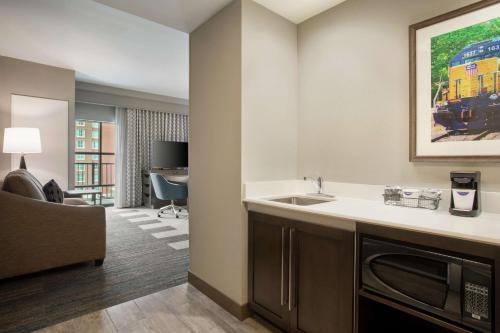 a kitchen with a sink and a living room at Hampton Inn Suites Kansas City Downtown Crossroads in Kansas City