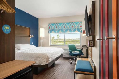um quarto de hotel com uma cama e uma cadeira e uma janela em Tru By Hilton Milwaukee Brookfield em Waukesha
