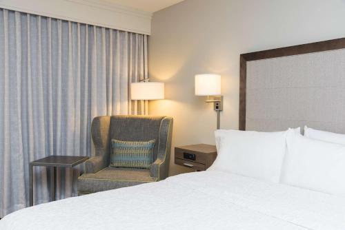 a hotel room with a bed and a chair at Hampton Inn Milwaukee Northwest in Milwaukee