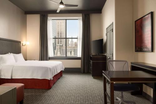 a hotel room with a bed and a desk and a window at Homewood Suites By Hilton Milwaukee Downtown in Milwaukee