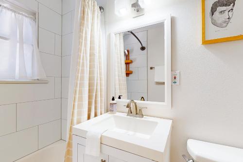 a white bathroom with a sink and a mirror at Stylish South Austin Cottage in Austin