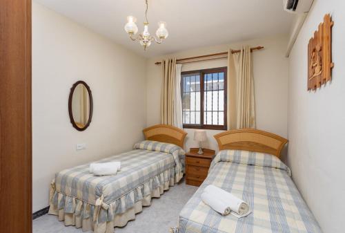een slaapkamer met 2 bedden en een spiegel bij Villa Alta Vista in Frigiliana