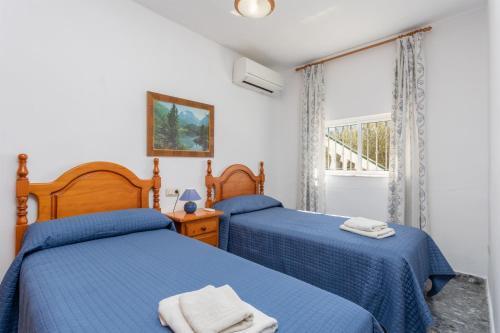 two beds in a bedroom with blue sheets and a window at Villa Casa Leo in Frigiliana