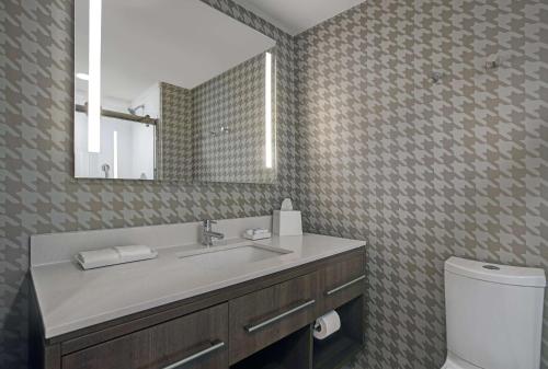 a bathroom with a sink and a mirror and a toilet at Home2 Suites By Hilton Milwaukee Downtown in Milwaukee