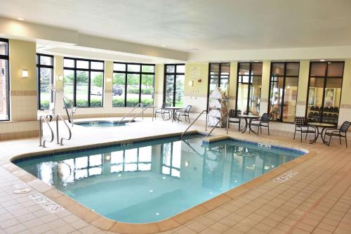 una gran piscina en un edificio con sillas y mesas en Hilton Garden Inn Oconomowoc en Oconomowoc
