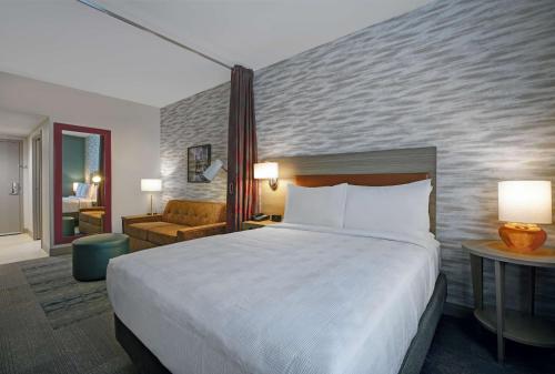 a hotel room with a bed and a living room at Home2 Suites By Hilton Milwaukee Downtown in Milwaukee