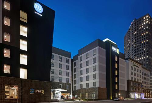密尔沃基Tru By Hilton Milwaukee Downtown, WI的夜晚城市中的两座高楼