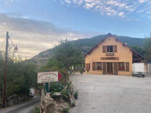 un letrero de la calle frente a un edificio con una casa en Ferme-auberge le cochon du Madres, en Escouloubre