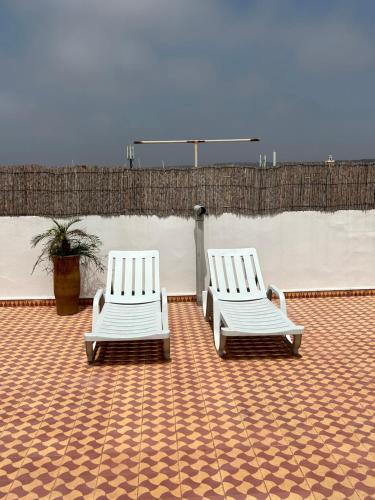 2 sedie bianche sedute sopra un patio di WELKAM Home & Coworking a Essaouira