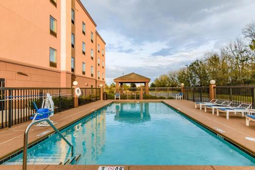 a swimming pool with chairs next to a building at Hampton Inn Foley in Foley