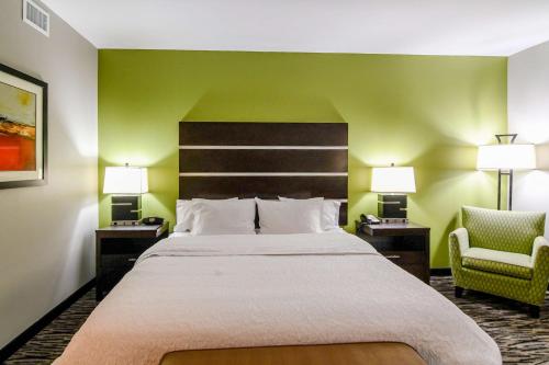 a hotel room with a large bed and two chairs at Hampton Inn Foley in Foley