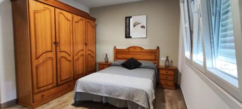 ein Schlafzimmer mit einem Bett und einem großen Holzschrank in der Unterkunft Piso céntrico in Pobra do Caramiñal