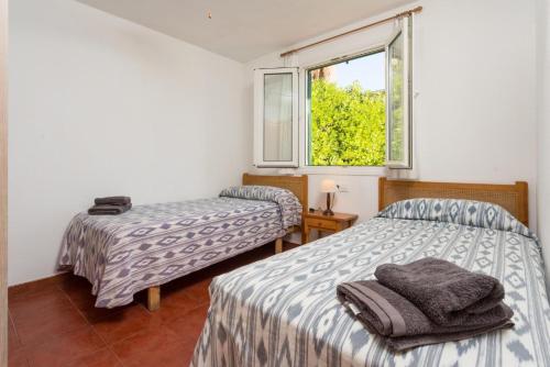 a room with two beds and a window at Villa Gelabert Ametller in Cala en Bosc