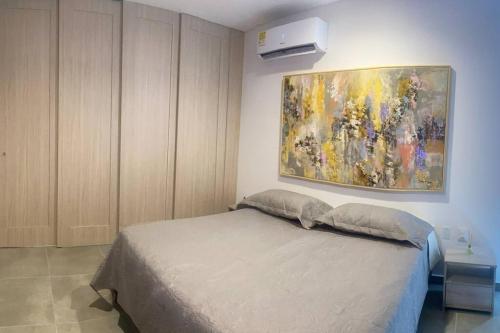 1 dormitorio con 1 cama y una pintura en la pared en Hermoso ApartaSuite en Playa Salguero!/Rodadero, en Gaira