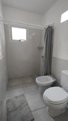 a white bathroom with a toilet and a window at Lo de Pepa-Sanatorio Allende Cerro in Córdoba
