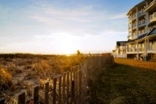 a fence next to a building next to a beach at Madison Beach Hotel, Curio Collection by Hilton in Madison