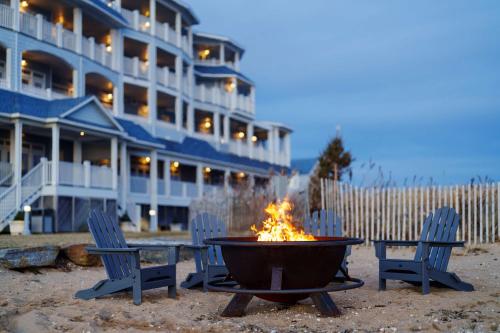 a fire pit with two chairs and a building at Madison Beach Hotel, Curio Collection by Hilton in Madison
