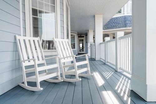two white rocking chairs sitting on the porch of a house at Madison Beach Hotel, Curio Collection by Hilton in Madison